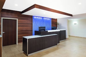 Uma área de recepção com painel de parede de madeira, um detalhe decorativo azul e um balcão de recepção.