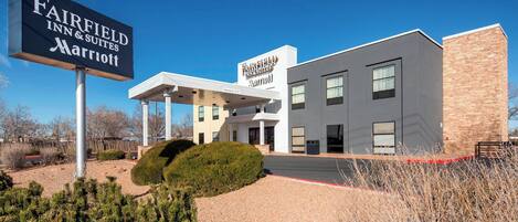 A Fairfield Inn & Suites Marriott hotel with a modern design, a covered outdoor area, and a gravel driveway.