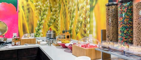 A breakfast buffet with cereal, fruits, and condiments.