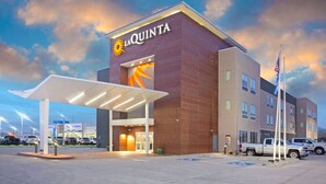 A hotel with a prominent sign, a covered entrance, and a parking area with vehicles. - La Quinta Inn & Suites by Wyndham Ponca City (Ponca City)