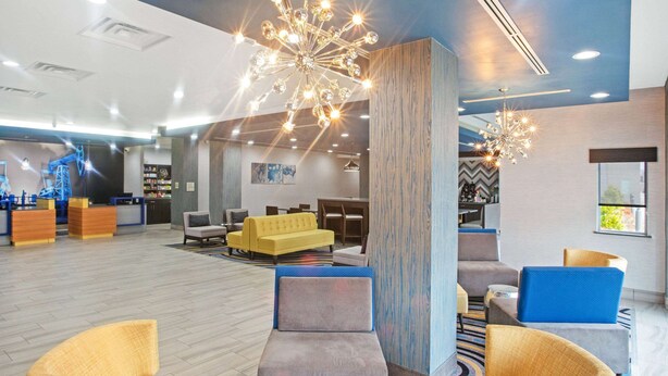 A spacious lobby with modern seating, a central light fixture, and a visible reception area. - La Quinta Inn & Suites by Wyndham Ponca City (Ponca City)