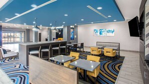 A modern restaurant with high ceilings, recessed lighting, and a blue accent wall. - La Quinta Inn & Suites by Wyndham Ponca City (Ponca City)
