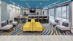A modern hotel lobby with a central seating area, a bar, and large windows offering a view. - La Quinta Inn & Suites by Wyndham Ponca City (Ponca City)
