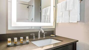 A bathroom with a large mirror, a sink, and a towel rack.
