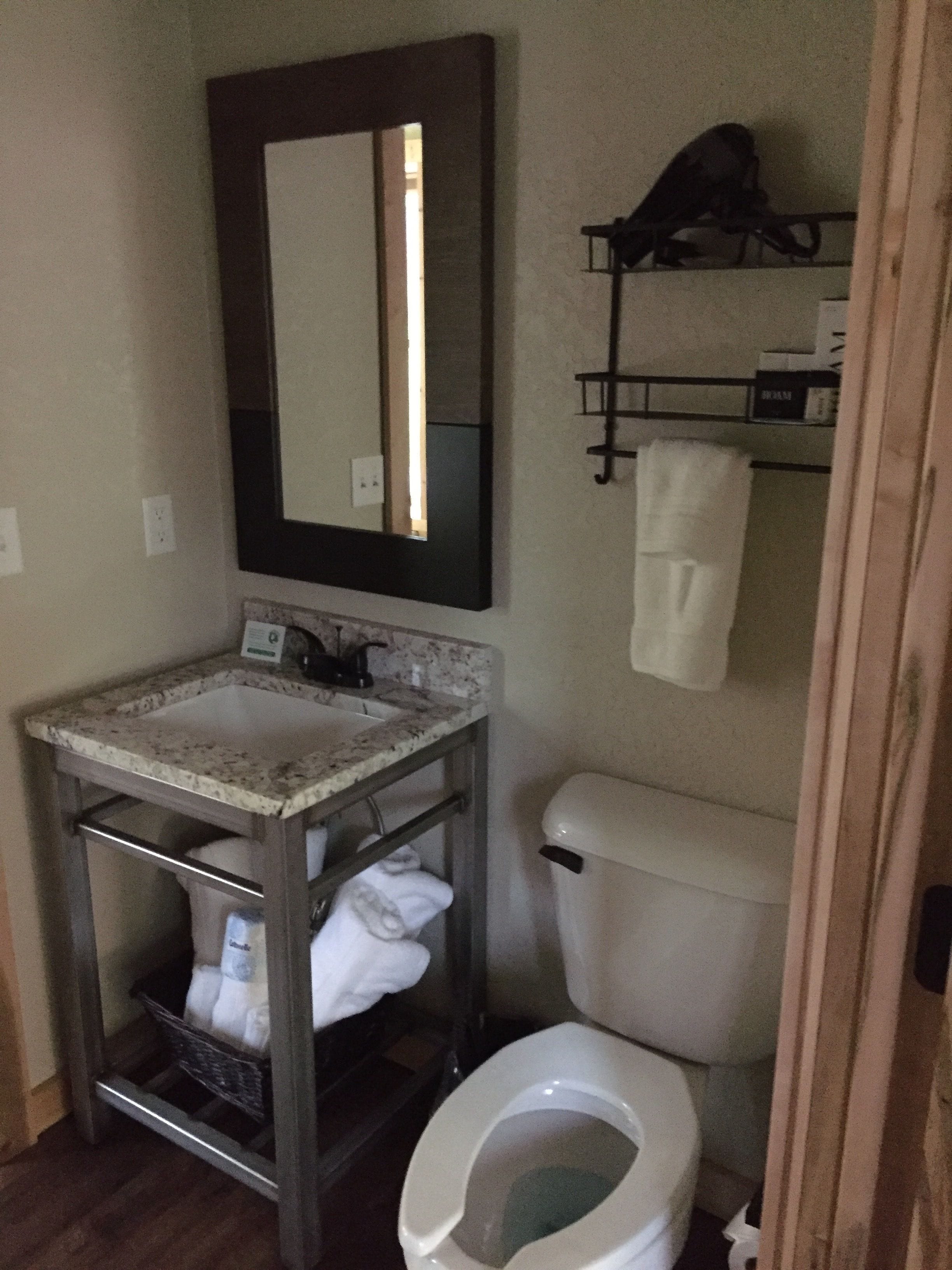 A bathroom with a sink, mirror, toilet, and towel rack.