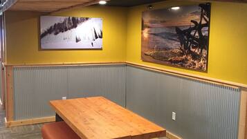 A corner room with a wooden table and bench, two wall-mounted pictures, and a textured floor.