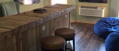 Zona de bar con taburetes de madera, una barra y dos lámparas fijadas a la pared.
