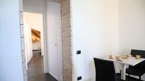 A dining area with a table set for four, a white door, and a hallway leading to another room.
