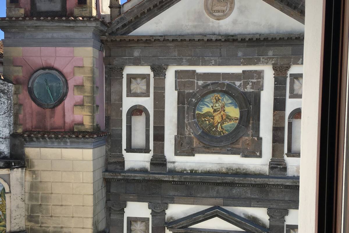 Un bâtiment historique doté d’une tour horloge, d’une grande arche centrale et d’une fresque murale.