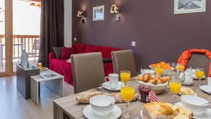 A dining area with breakfast items, a red sofa, and a view of the outdoors. - Chalet in Paradiski with Pool & Spa (Plagne Villages)