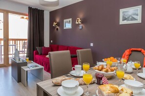 A dining area with breakfast items, a red sofa, and a view of the outdoors. - Chalet in Paradiski with Pool & Spa (Plagne Villages)