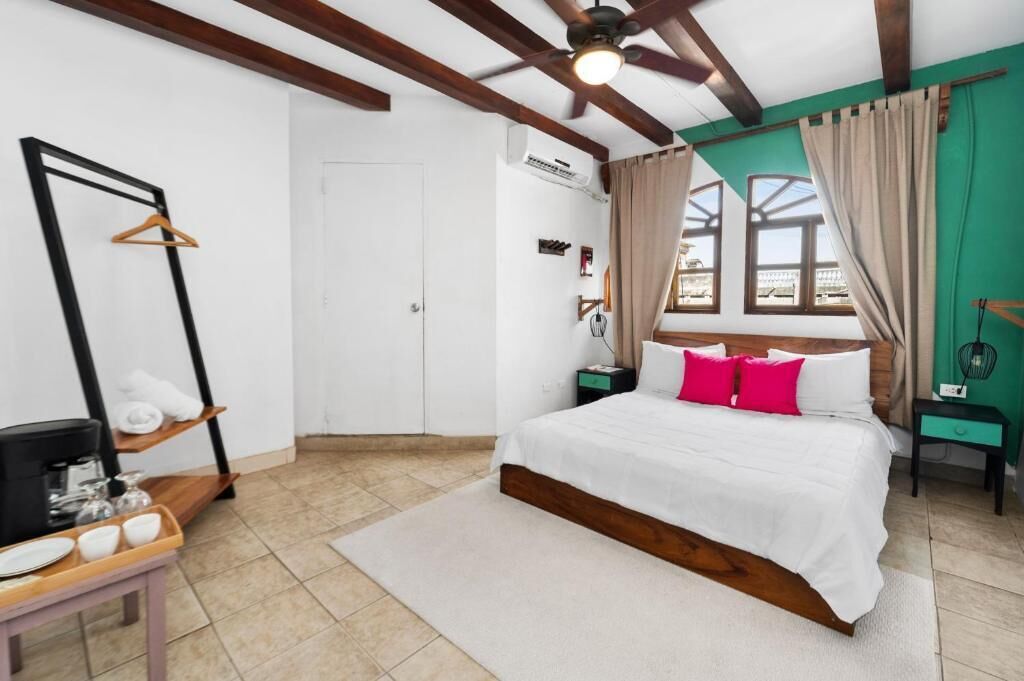 A bedroom with a bed, a hanging clothes rack, a coffee station, and a view of the outside.