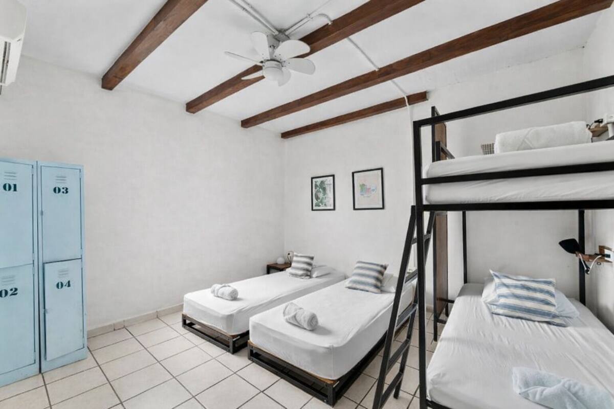 A dormitory room with bunk beds, a ceiling fan, and lockers.
