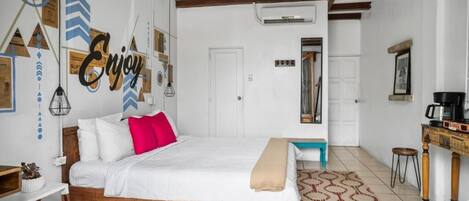 Une chambre à coucher comprenant un lit, un bureau, une chaise, un ventilateur de plafond et un tapis à motifs.