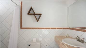 Un baño con inodoro, lavamanos y cortina de ducha.