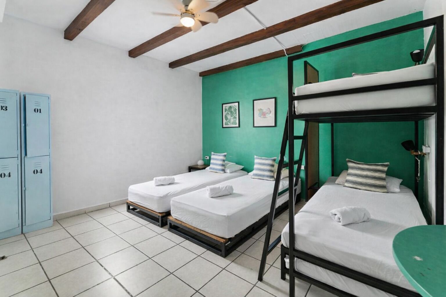Una habitación con literas, ventilador de techo y taquillas.