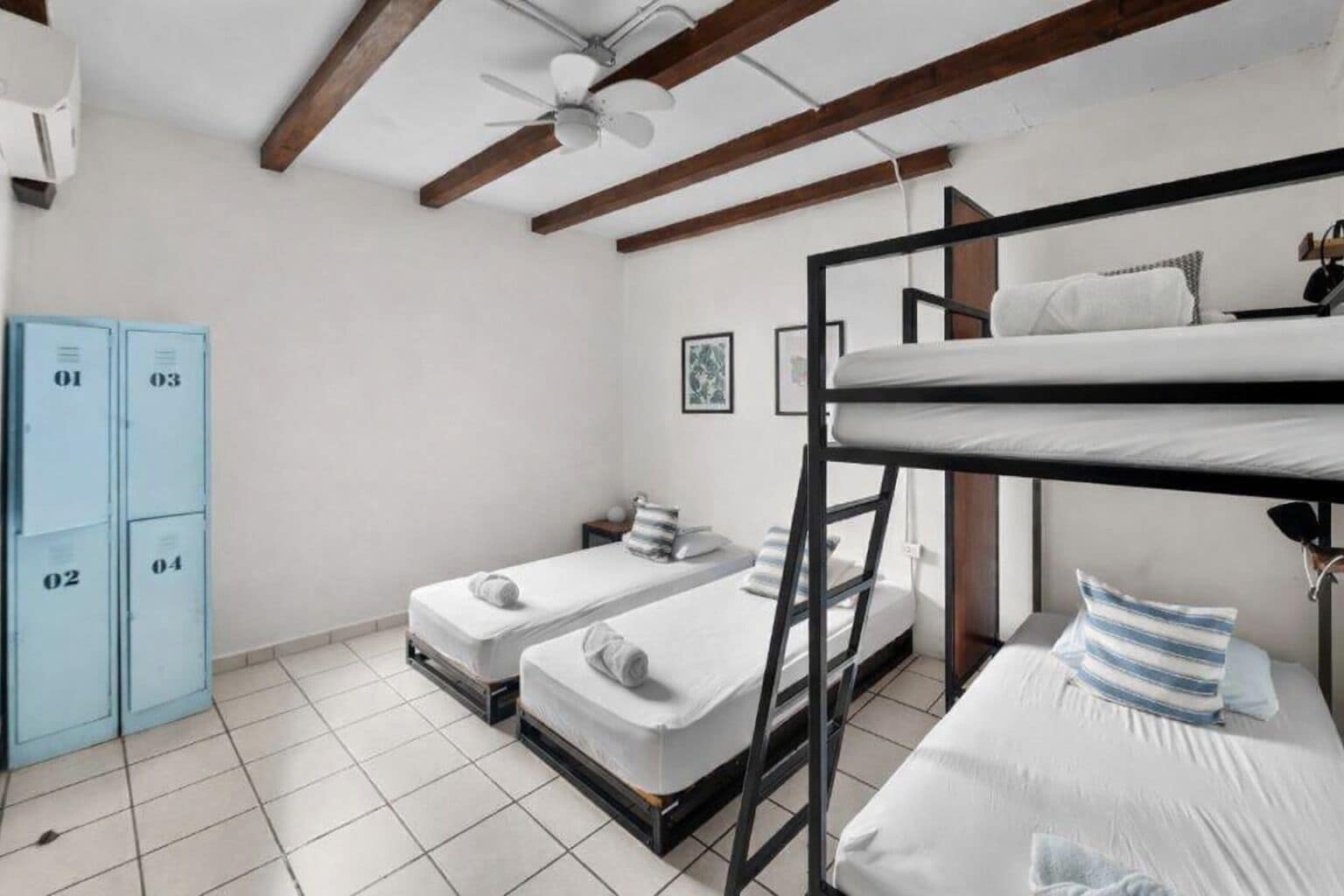 A dormitory room with bunk beds, a ceiling fan, and lockers.