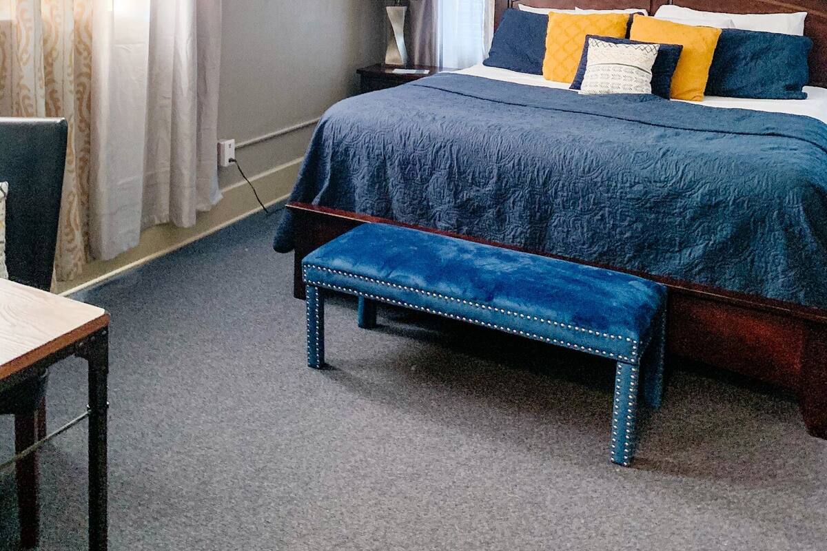 A bedroom with a bed, a desk, a chair, a lamp, and a ceiling fan.