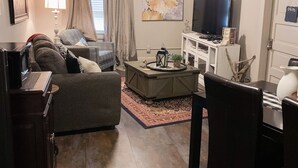Una sala de estar con sofá, mesa de centro, televisor y escritorio con silla.