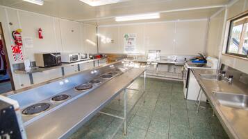 A kitchen with stainless steel appliances, a fire extinguisher, and a sign indicating no cooking after 10 PM.