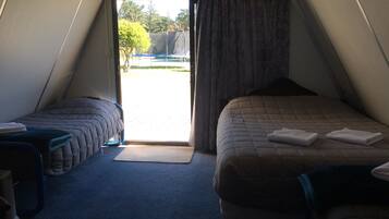 A room with two beds, a small table, and a window with curtains.