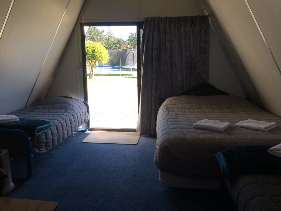 A room with two beds, a small table, and a window with curtains.