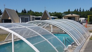 Un área de piscina con estructuras de techo transparentes y suelo de grava.