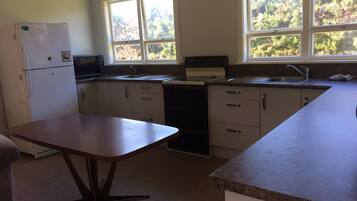 A compact kitchen with a refrigerator, microwave, sink, and stove.