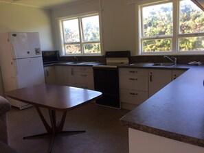 A compact kitchen with a refrigerator, microwave, sink, and stove.