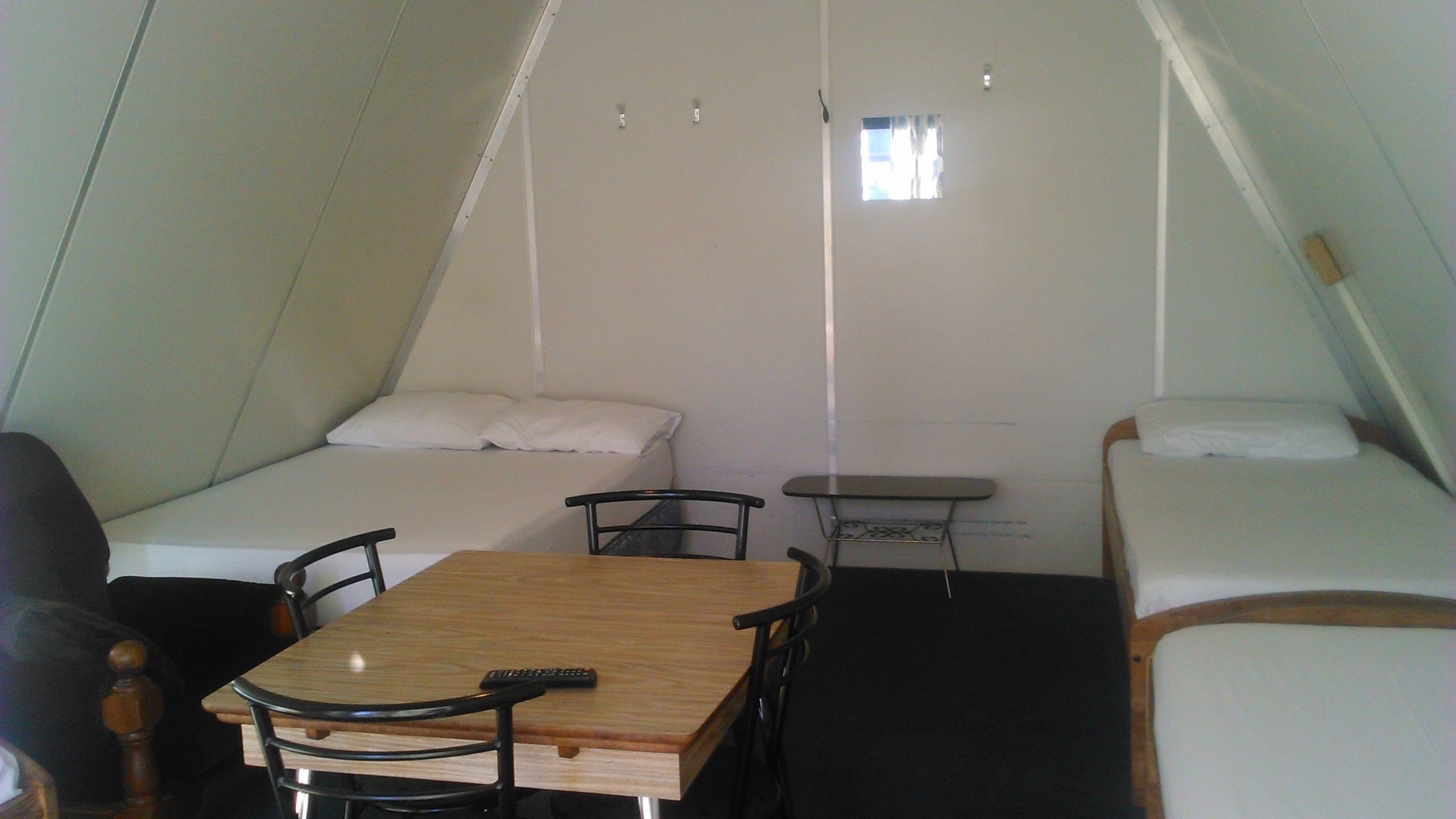A compact, triangular room with two beds, a small table, and chairs.