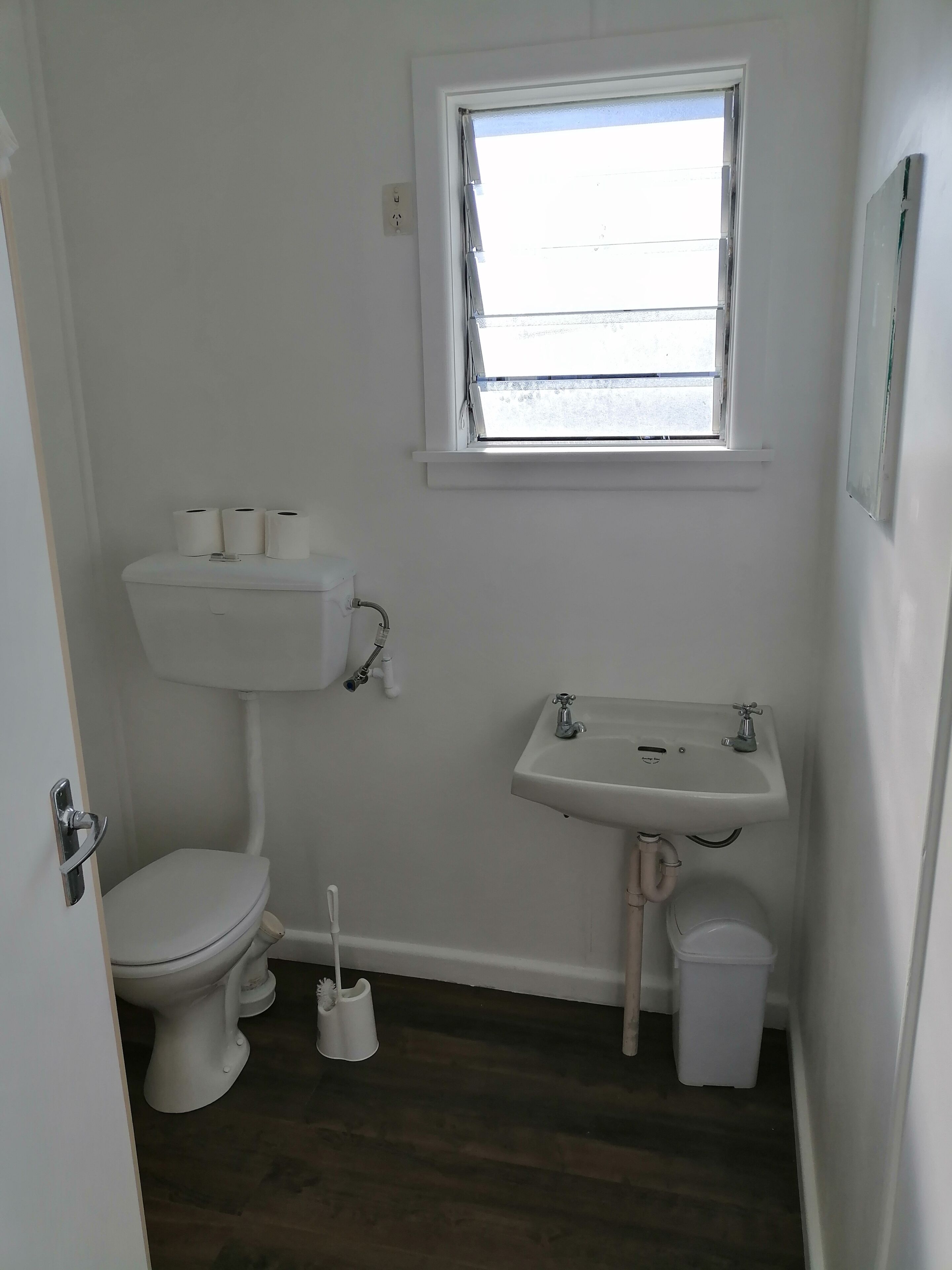 A small, clean bathroom with a toilet, sink, and window.