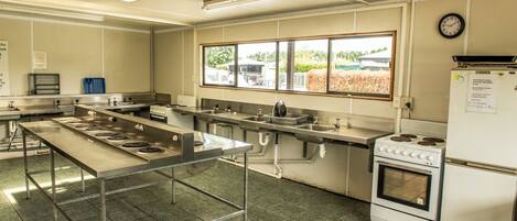 A commercial kitchen with stainless steel appliances, a large central island, and a view through the windows.