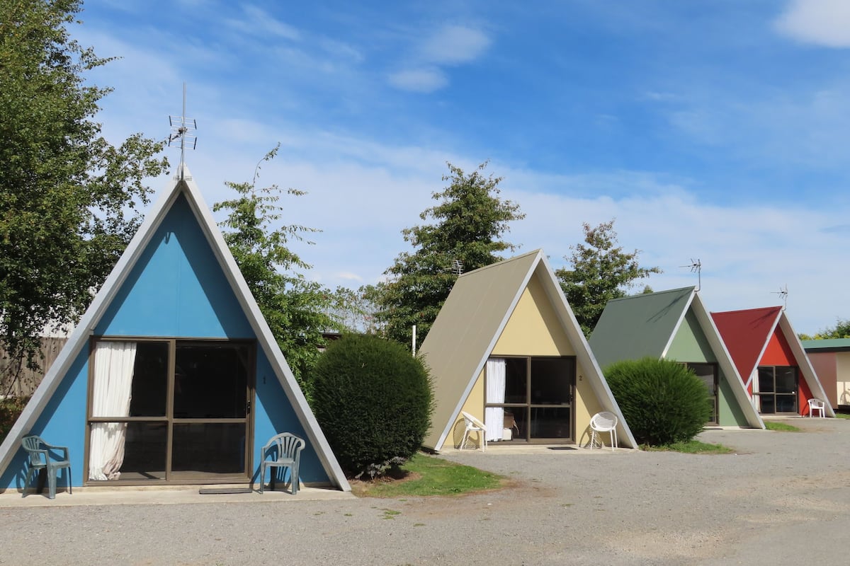 A row of triangular A-frame cabins with sliding glass doors and outdoor seating.