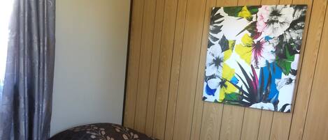 A hotel room with two beds, a wooden panel wall, and a floral painting.