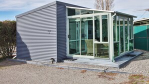 Un edificio moderno de una sola planta con un amplio ventanal y ventanas, camino de grava y revestimiento de metal.