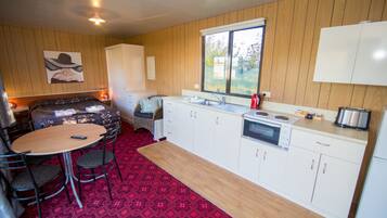 Una cocina compacta con comedor, paredes de madera, alfombra roja estampada y ventana con vistas.