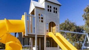 Un parque infantil con una casita de juegos y toboganes.