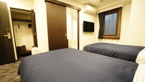 A hotel room with two beds, a wardrobe, a television, and an air conditioning unit. - Hotel LiVEMAX Nagoya Sakae East (Nagoya)