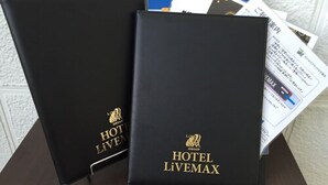 Two black binders with 'HOTEL LIVEMAX' branding and a logo, placed on a table with some papers. - Hotel LiVEMAX Nagoya Sakae East (Nagoya)