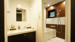 A modern bathroom with a white sink, dark cabinets, a mirror, and a shower area. - Hotel LiVEMAX Nagoya Sakae East (Nagoya)