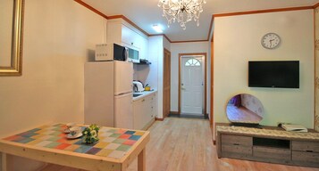 Una cocina compacta con microondas, refrigerador y una pequeña mesa de comedor con mantel a cuadros.