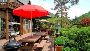 A wooden deck with picnic tables and a barbecue grill. - Sanwoolrim Pension (Yangyang)