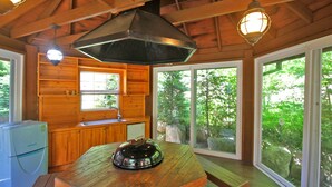 A cabin with a wooden interior, a kitchen area with a sink, a stove, and a dining table with a kettle. - Sanwoolrim Pension (Yangyang)