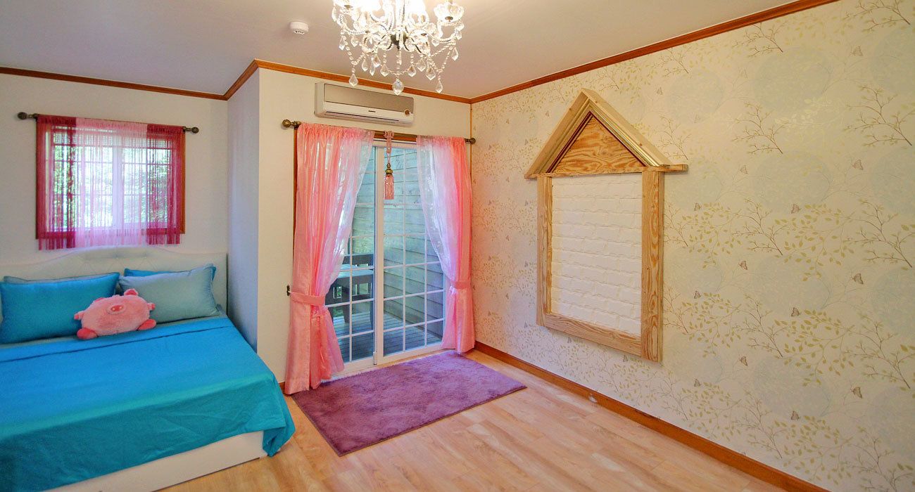 A bedroom with a bed, a window with curtains, a wooden wall panel, and a chandelier.