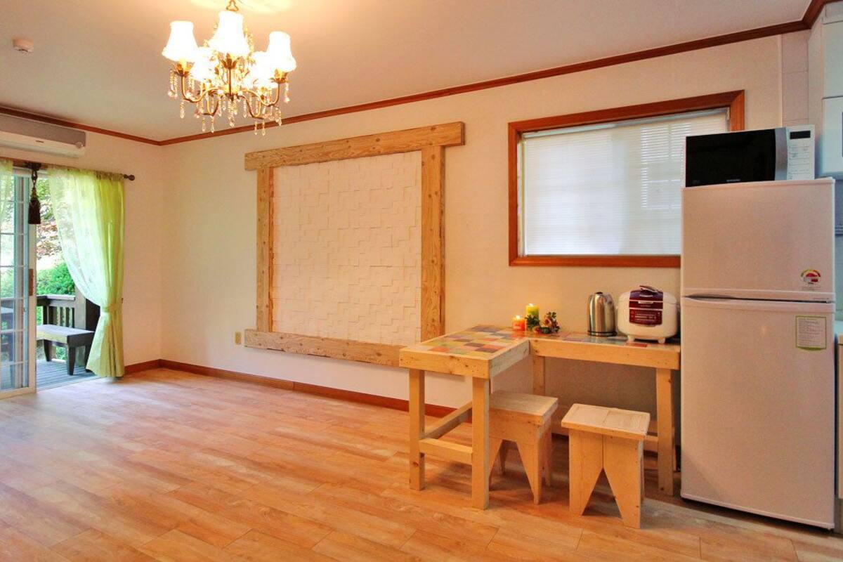 Una cocina con una mesa de madera, un refrigerador y una ventana con persianas.