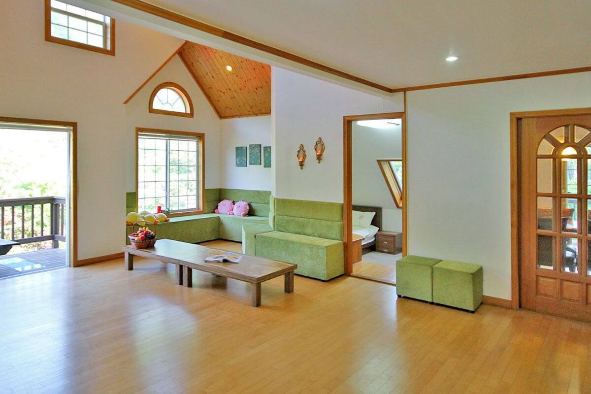 Un salón amplio con techo alto, ventanas grandes y una zona de estar acogedora con sofá y una mesita de centro.
