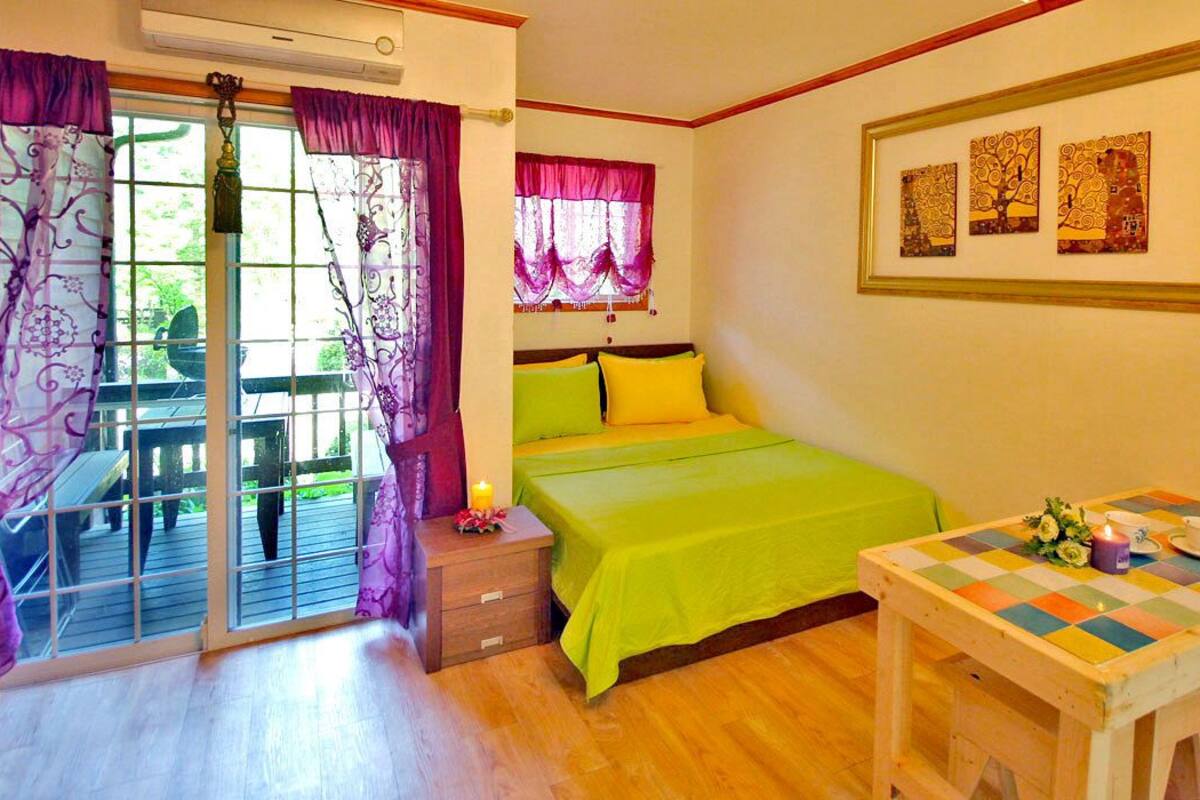 Un dormitorio con cama, una mesa y una ventana con cortinas.