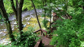 A wooden deck with a view of a clear stream surrounded by trees. - Sanwoolrim Pension (Yangyang)