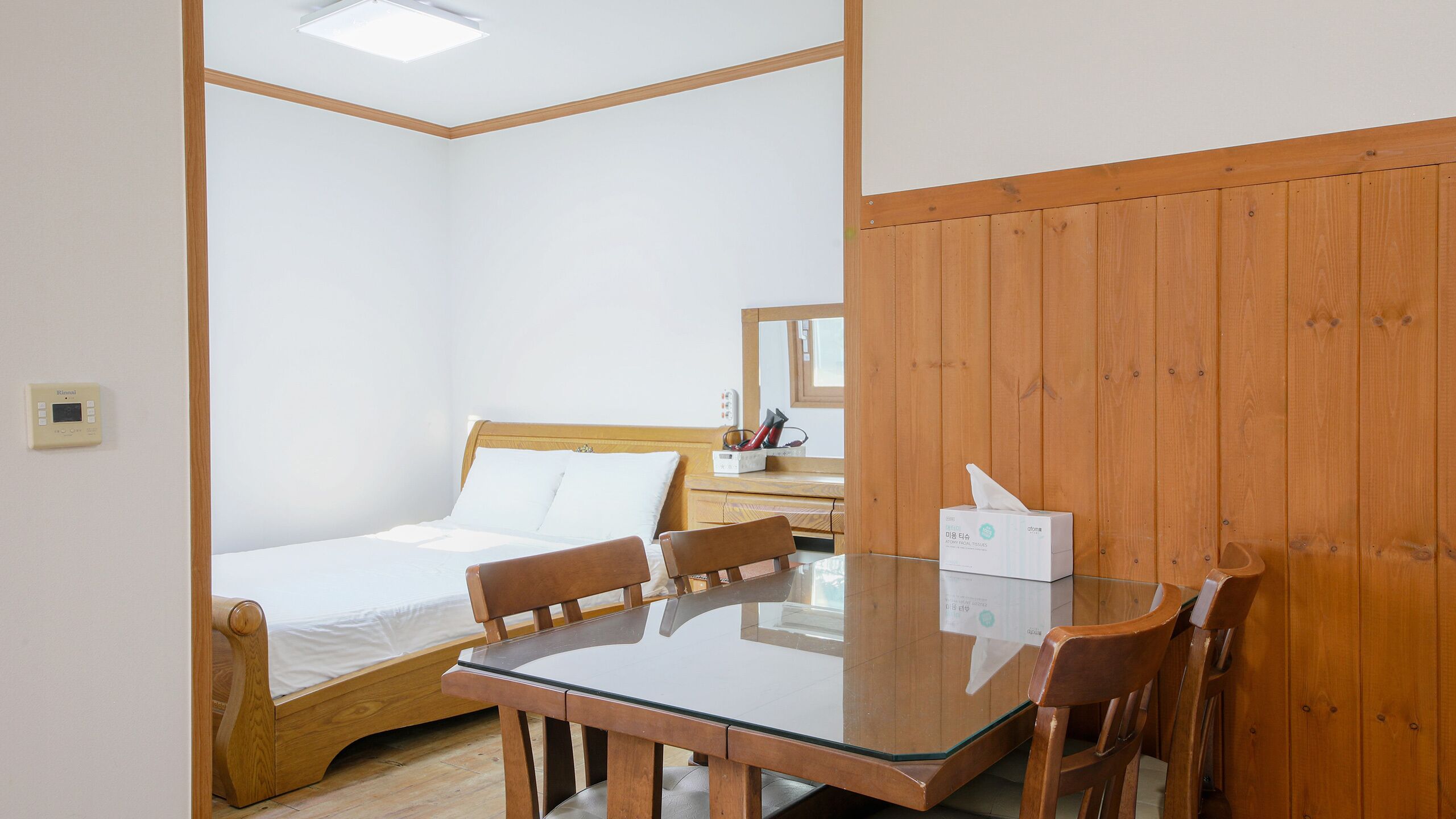 Una camera da letto con un letto, un armadio in legno, un comodino con uno specchio e un tavolo con sedie.