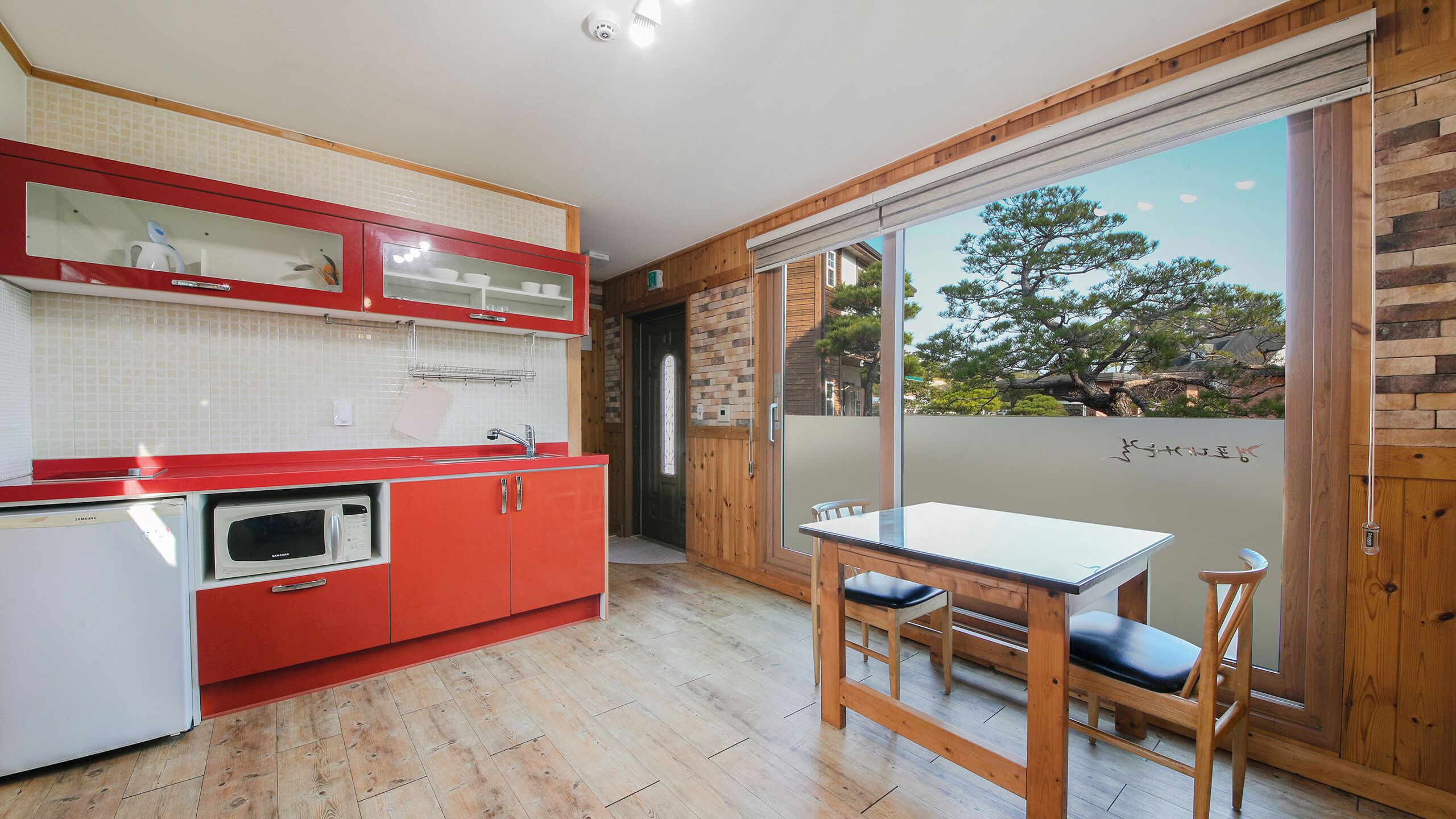 Una cocina moderna con armarios rojos, un microondas y un comedor con mesa y sillas.